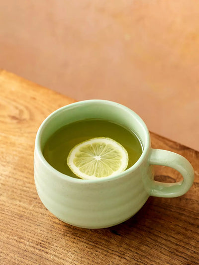 Green mug with lemon slice on a wooden surface. Mulveys.ie